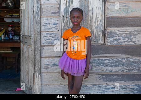 Ritratto di giovane Afro-Surinamese con capelli intrecciati di fronte a casa in legno nel villaggio Aurora, Sipalivini Distretto, Suriname / Surinam Foto Stock