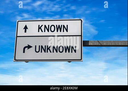 Segnale stradale con parole conosciute e sconosciute. Due cartelli stradali bianchi con freccia sul palo in metallo. Strada direzionale, segnale Crossroads Road, due frecce blu Foto Stock