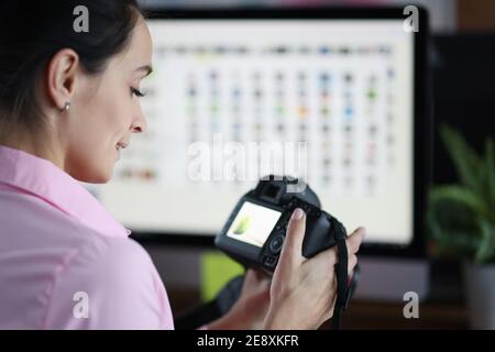 Giovane donna che tiene la fotocamera in mano e guarda le foto Foto Stock