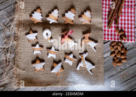 Vista dall'alto di biscotti fatti in casa a forma di albero di Natale, stelle e renne su tele placemat su sfondo tavola di legno Foto Stock