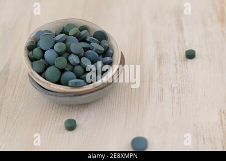 Spirulina alghe verde in compresse in tazze rotonde in ceramica su un legno chiaro sfondo shabby..Dietary supplements.Super food. Alghe biologiche sane Foto Stock