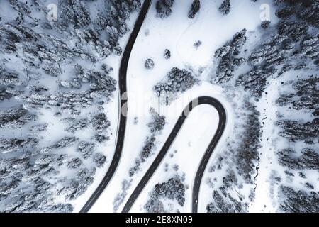 Vista aerea della strada di montagna vuota nei boschi innevati Foto Stock