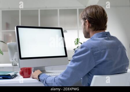 Vista posteriore di un uomo d'affari caucasico seduto alla scrivania per fare video chiamare utilizzando un computer desktop Foto Stock