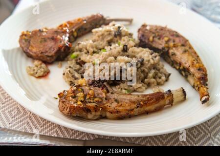 Costoletta di agnello marinata alla griglia con risotto di funghi cheesy Foto Stock