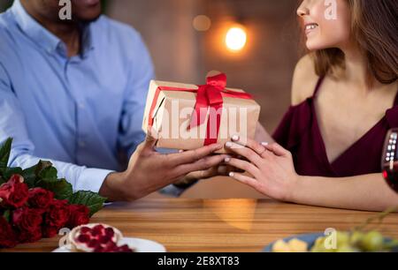 Festa di San Valentino. Uomo nero che dà scatola del regalo alla sua ragazza felice Foto Stock
