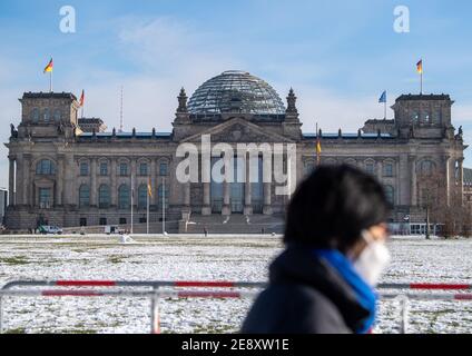 Berlino, Germania. 01 Feb 2021. Una donna con bocca-naso che copre passeggiate da Reichstag edificio Credit: Dorothée Barth/dpa/Alamy Live News Foto Stock