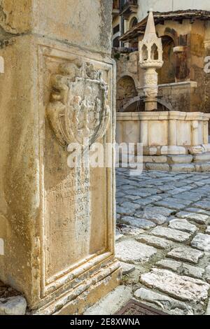 Lo stemma di Fontecchio inciso sulla pietra alla fine della scalinata che porta alla piazza medievale. Fontecchio, Abruzzo, Italia Foto Stock