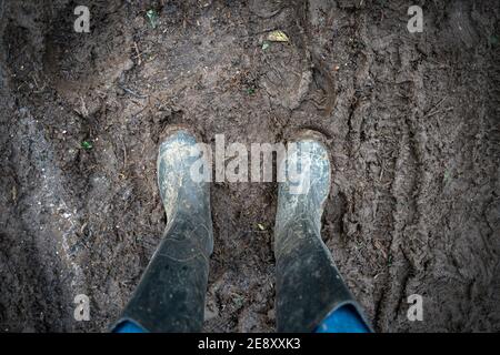 paio di stivali wellington fangosi in piedi nel fango. Foto Stock