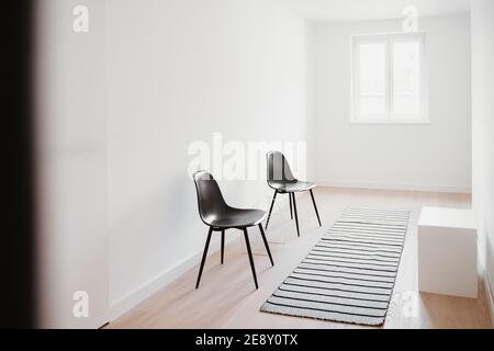 due sedie nere in una stanza bianca Foto Stock