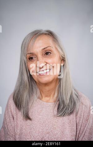 Vista frontale ritratto di donna anziana felice in piedi all'interno di casa. Foto Stock
