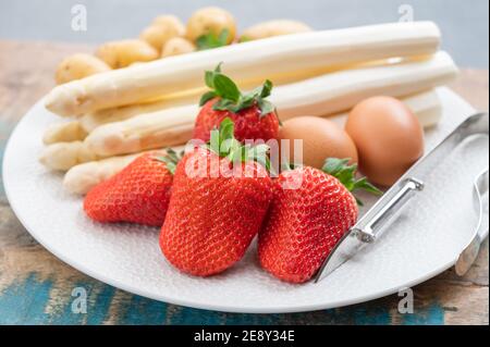 Primavera nei Paesi Bassi, asparagi bianchi olandesi di alta qualità, lavati e sbucciati a bordo con fragola matura fresca Foto Stock