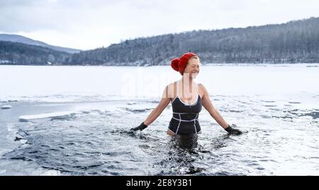 Vista frontale della donna anziana attiva in costume da bagno all'aperto in acqua in inverno, concetto di terapia fredda. Foto Stock