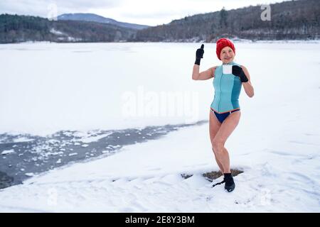 Vista frontale della donna anziana attiva in costume da bagno all'aperto in inverno, concetto di terapia fredda. Foto Stock