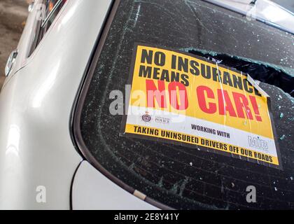 Nessuna assicurazione significa nessun adesivo auto rilasciato dalla polizia bloccato su parabrezza schiacciato di auto sequestrata da conducente recuperato da poliziotti di traffico per la violazione della legge Foto Stock