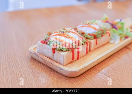 pane, salsa di avocado, pancetta, spinaci, uovo benedetto sul piatto bianco e sfondo di legno vecchio, salsa di avocado unire avocado e pomodori, prima colazione Foto Stock