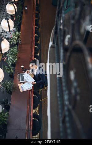 Freelance maschile focalizzato dai capelli scuri che si occupa di documenti cartacei Foto Stock
