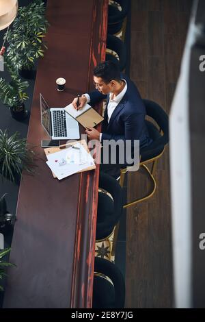 Concentrato elegante maschio in occhiali prendendo appunti Foto Stock