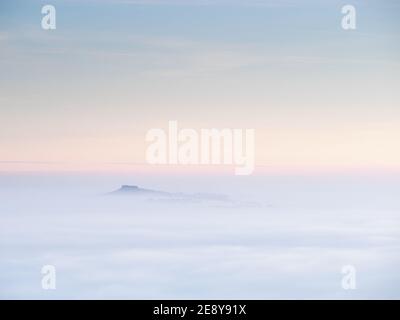 Almscliffe Crag sbircia attraverso un mare di nebbia durante un'inversione di temperatura autunnale nel Wharfedale inferiore, con il resto del paesaggio oscurato. Foto Stock