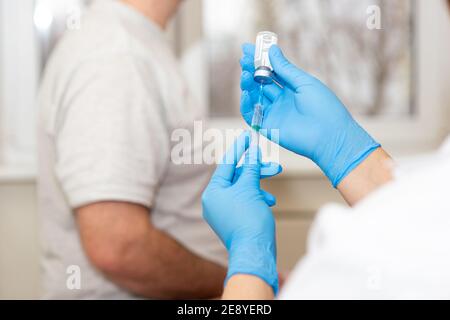 Un medico o un infermiere si prepara a vaccinare un paziente Foto Stock