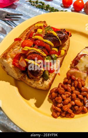 Sandwich con cipolle e peperoni di salsiccia con lato di cotto Fagioli e insalata di patate tedesca Foto Stock