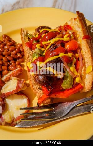 Sandwich con cipolle e peperoni di salsiccia con lato di cotto Fagioli e insalata di patate tedesca Foto Stock