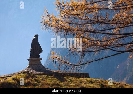 Monumento all'alpinista Julius Kugy nella valle del Trenta con l'albero di larice d'autunno a fianco. Foto Stock