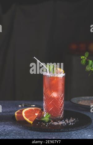 Pompelmo rosa Mezcal Paloma cocktail in calice con gocce d'acqua sul tavolo in vera casa. Nuovo concetto di vita della quarantena. Primo piano, dep. Bassa Foto Stock