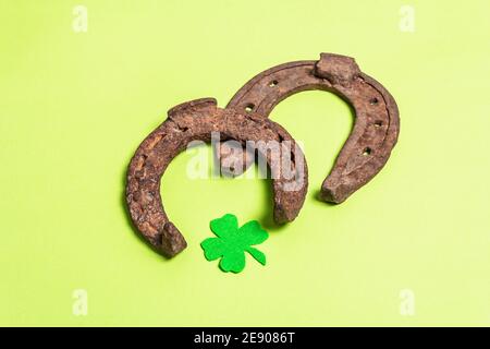 Ferro di cavallo gravemente usurato con una foglia di trifoglio in feltro. Simbolo di buona fortuna, concetto di giorno di San Patrizio. Sfondo verde opaco Foto Stock