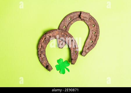 Ferro di cavallo gravemente usurato con una foglia di trifoglio in feltro. Simbolo di buona fortuna, concetto di giorno di San Patrizio. Sfondo verde opaco Foto Stock