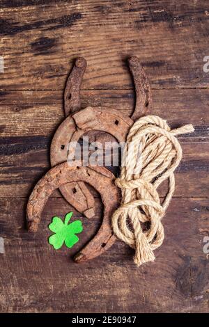 Ferro di cavallo, corda e foglia di trifoglio in feltro mal indossati. Simbolo di buona fortuna, concetto di giorno di San Patrizio. Vintage tavole di legno sfondo Foto Stock