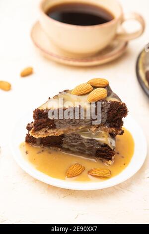 Pezzi di torta brownie al cioccolato con crema al caramello e mandorle su fondo bianco di cemento. Vista laterale, primo piano, messa a fuoco selettiva. Foto Stock