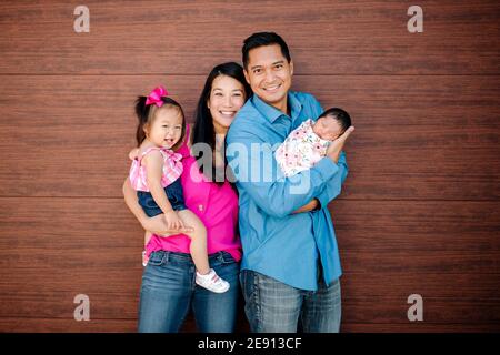 Mamma felice, papà, bambino e neonato di fronte alla porta del garage in legno Foto Stock