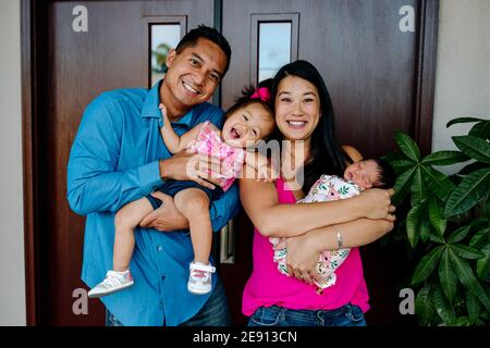 Ridendo la famiglia asiatica-americana con la figlia neonato e l'anno Foto Stock