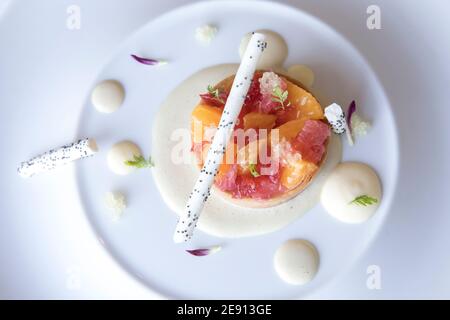 Colorato dessert gourmet di crostata di agrumi con bastoncini di cioccolato bianco Foto Stock