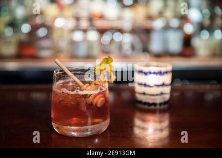 Cocktail rosso colorato di ispirazione autunnale sul piano bar in interni accoglienti Foto Stock