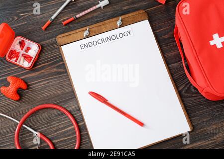 Appunti con parola ENDOCRINOLOGIA, ghiandola tiroidea, siringhe, stetoscopio e pillole su sfondo di legno Foto Stock