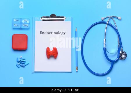 Appunti con parola ENDOCRINOLOGIA, ghiandola tiroidea, stetoscopio e pillole su sfondo a colori Foto Stock