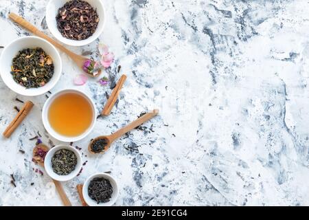 Tazza di tè e ciotole con foglie secche sul tavolo Foto Stock