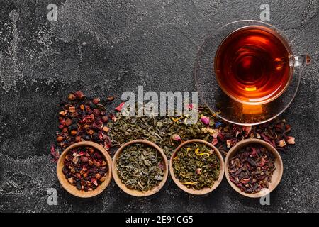 Composizione con tazza e foglie di tè secco su sfondo scuro Foto Stock