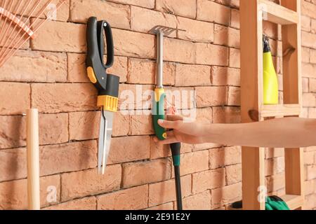 Mano femminile con attrezzi da giardinaggio in fienile Foto Stock