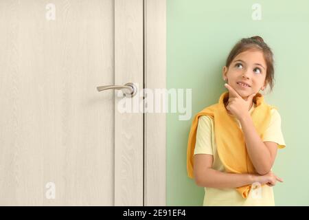 Pensieroso bambina in piedi vicino a porta chiusa Foto Stock