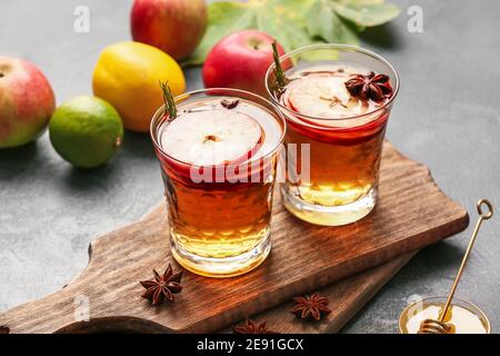 Bevanda gustosa con spezie e fette di mela nei bicchieri sfondo scuro Foto Stock