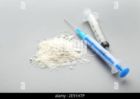 Cocaina con siringhe su sfondo grigio Foto Stock