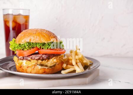 Vassoio con gustosi hamburger e patatine fritte su sfondo chiaro Foto Stock
