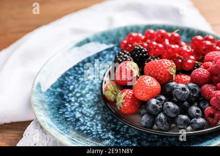 Piatto con diversi frutti di bosco gustosi su tavolo di legno Foto Stock