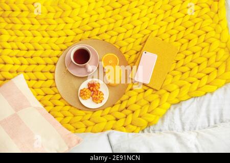 Vassoio con gustosa colazione, prenotazione e sul telefono cellulare a letto Foto Stock