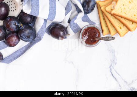 Vaso in vetro con deliziosa marmellata di prugne fatta in casa su sfondo chiaro Foto Stock