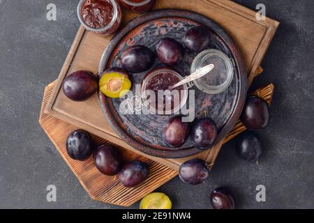 Composizione con deliziosa marmellata di prugne fatta in casa su sfondo scuro Foto Stock