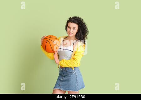 Ritratto di giovane donna elegante con palla per giocare a basket su sfondo a colori Foto Stock