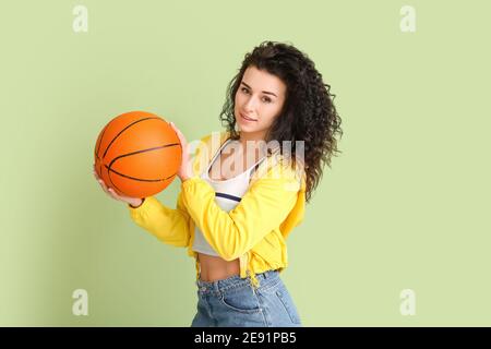 Ritratto di giovane donna elegante con palla per giocare a basket su sfondo a colori Foto Stock